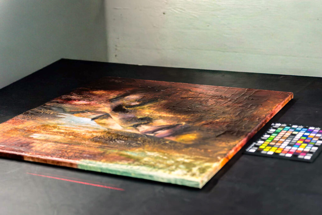 Ein Gemälde liegt auf dem Scantisch, eine Farbkarte liegt daneben